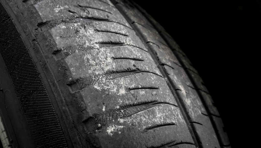 Tire wear concept. Danger of using old car bald tire with very little tread remaining.