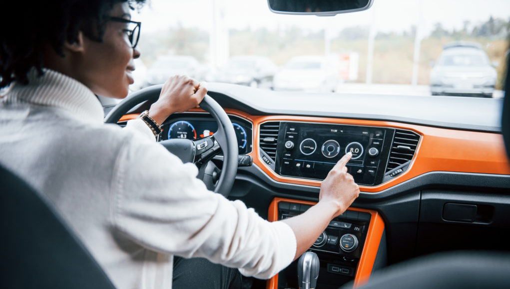 Young african american woman sits inside of new modern car