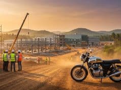 Usine Royal Enfield : le pari industriel de Tirupati Une moto Royal Enfield stationnée devant un chantier industriel en construction à Tirupati au coucher du soleil.