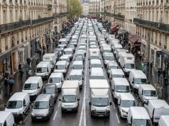 Embouteillages et logistique à Paris : l’étude Geotab 2026 Vue en plongée d'une rue parisienne saturée par une file dense de camionnettes de livraison blanches.