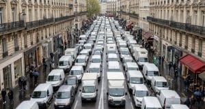 Embouteillages et logistique à Paris : l’étude Geotab 2026 Vue en plongée d'une rue parisienne saturée par une file dense de camionnettes de livraison blanches.