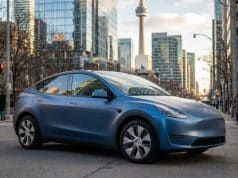 Voiture électrique chinoise : l’accord qui change le Canada Une Tesla Model Y bleu mat circulant dans une rue animée de Toronto avec la tour CN en arrière-plan.