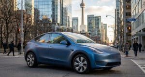 Voiture électrique chinoise : l’accord qui change le Canada Une Tesla Model Y bleu mat circulant dans une rue animée de Toronto avec la tour CN en arrière-plan.