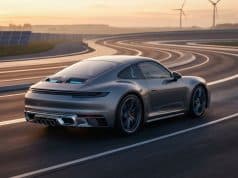 Porsche 911 électrique : la fin du tout-électrique Une Porsche 911 grise roulant sur une piste sinueuse au coucher du soleil, entourée de panneaux solaires et d'éoliennes.