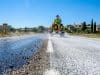 Lait de chaux et routes : la solution face à la canicule Un ouvrier en engin pulvérise du lait de chaux blanc sur une route sombre pour réduire la chaleur lors d'une canicule.