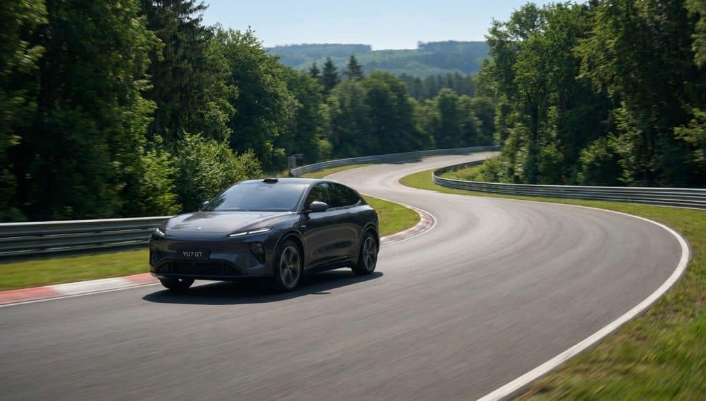 La voiture électrique Xiaomi YU7 GT grise circulant sur une courbe du circuit du Nürburgring entouré de forêt.