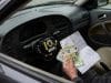 Rappel airbag Takata Saab : la facture s’alourdit en France Une main tenant des billets en euros et une facture à l'intérieur d'une voiture Saab avec un airbag démonté.