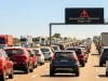 Prévisions Bison Futé : trafic noir les 10 et 11 juillet Vue arrière d'un important embouteillage sur une autoroute sous un ciel bleu avec un panneau d'avertissement lumineux.