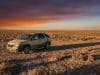 La Pontiac Aztek de Walter White : un choix artistique Une Pontiac Aztek beige stationnée seule dans un désert aride sous un coucher de soleil orange et violet.