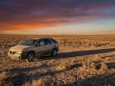 La Pontiac Aztek de Walter White : un choix artistique Une Pontiac Aztek beige stationnée seule dans un désert aride sous un coucher de soleil orange et violet.