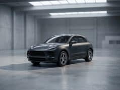 Fin de production du Macan thermique : quel avenir pour Porsche ? Un SUV Porsche Macan gris stationné au centre d'un vaste studio industriel au béton brut et à la lumière tamisée.