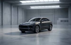 Fin de production du Macan thermique : quel avenir pour Porsche ? Un SUV Porsche Macan gris stationné au centre d'un vaste studio industriel au béton brut et à la lumière tamisée.