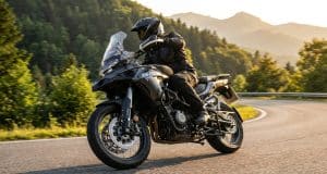 Essai QJ Motor SRT 450 RX : le trail A2 au prix imbattable Un motard en équipement noir chevauche une moto trail QJ Motor SRT 450 RX grise sur une route sinueuse en montagne.