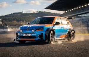 Kit carrosserie Milltek pour Renault 5 : l’hommage Groupe B Une Renault 5 électrique aux couleurs de course bleue et orange, équipée d'un kit carrosserie large sur un circuit.