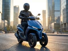 Yamaha Tricity 300 2026 : l’airbag au service de votre sécurité Un pilote à moto sur un scooter à trois roues Yamaha Tricity bleu circulant dans un quartier d'affaires au coucher.