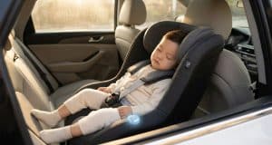Dispositif anti-oubli enfant voiture : sécurité et loi Un jeune enfant dort paisiblement dans un siège auto équipé d'un capteur anti-oubli lumineux.