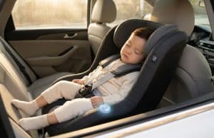 Dispositif anti-oubli enfant voiture : sécurité et loi Un jeune enfant dort paisiblement dans un siège auto équipé d'un capteur anti-oubli lumineux.