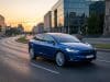 Ventes Tesla Model Y en Europe : analyse d’un succès majeur Une voiture électrique Tesla bleue roulant sur une route urbaine moderne au coucher du soleil.