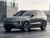 Volvo EX90 lidar abandon : les causes d’un échec technique Le SUV électrique gris Volvo EX90 stationné sur une route mouillée devant un bâtiment moderne.