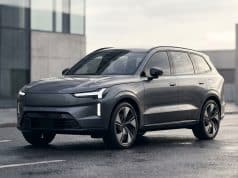 Volvo EX90 lidar abandon : les causes d’un échec technique Le SUV électrique gris Volvo EX90 stationné sur une route mouillée devant un bâtiment moderne.