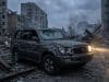 Le Volkswagen Touareg survit à un bombardement en Ukraine Un SUV Toyota gris endommagé avec un phare allumé, garé au milieu des décombres d'une ville ukrainienne dévastée.