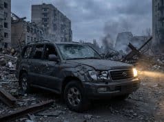 Le Volkswagen Touareg survit à un bombardement en Ukraine Un SUV Toyota gris endommagé avec un phare allumé, garé au milieu des décombres d'une ville ukrainienne dévastée.