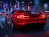 Brevet Ferrari feux arrière : le futur de l’aérodynamique Une voiture de sport rouge Ferrari circulant de nuit sur une autoroute urbaine, mettant en avant ses feux arrière innovants.
