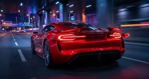 Brevet Ferrari feux arrière : le futur de l’aérodynamique Une voiture de sport rouge Ferrari circulant de nuit sur une autoroute urbaine, mettant en avant ses feux arrière innovants.