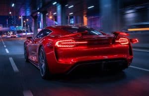Brevet Ferrari feux arrière : le futur de l’aérodynamique Une voiture de sport rouge Ferrari circulant de nuit sur une autoroute urbaine, mettant en avant ses feux arrière innovants.