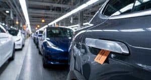 Rappel voitures poignées porte : la Chine face au danger Gros plan sur une poignée de porte de voiture avec une étiquette orange indiquant un défaut de mécanisme en usine.