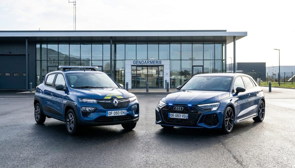 Une Renault Spring et une Audi RS3 aux couleurs de la Gendarmerie garées devant une caserne.