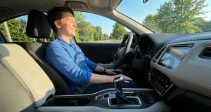Le permis boîte automatique : une formation simplifiée Un jeune homme souriant au volant d'une voiture à boîte automatique lors d'une journée ensoleillée.