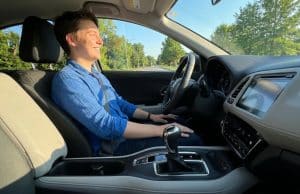 Le permis boîte automatique : une formation simplifiée Un jeune homme souriant au volant d'une voiture à boîte automatique lors d'une journée ensoleillée.