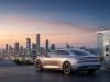 Marché voiture électrique : prévisions et indépendance Voiture électrique moderne en charge devant une skyline urbaine au coucher du soleil avec des panneaux solaires et éoliennes.