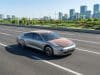 Voiture solaire Luminetta : vers une autonomie énergétique La voiture solaire argentée Luminetta roule sur une route moderne avec des panneaux solaires visibles sur le toit et capot.