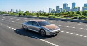 Voiture solaire Luminetta : vers une autonomie énergétique La voiture solaire argentée Luminetta roule sur une route moderne avec des panneaux solaires visibles sur le toit et capot.