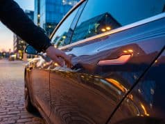Rappel Tesla en Chine : le défi des poignées de sécurité Gros plan sur une main s'approchant de la poignée affleurante d'une Tesla garée dans une rue urbaine au crépuscule.