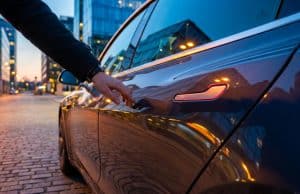 Rappel Tesla en Chine : le défi des poignées de sécurité Gros plan sur une main s'approchant de la poignée affleurante d'une Tesla garée dans une rue urbaine au crépuscule.