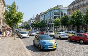 Marché voiture électrique Europe : bilan de juillet 2026 Une Renault 5 électrique colorée circulant sur une rue pavée bordée de voitures et d'immeubles européens ensoleillés.