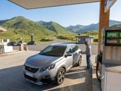 Économies et prix carburant en Andorre : l’analyse complète Un homme fait le plein de sa voiture dans une station-service en Andorre avec les montagnes en arrière-plan.