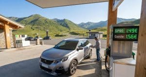 Économies et prix carburant en Andorre : l’analyse complète Un homme fait le plein de sa voiture dans une station-service en Andorre avec les montagnes en arrière-plan.