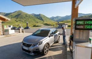 Économies et prix carburant en Andorre : l’analyse complète Un homme fait le plein de sa voiture dans une station-service en Andorre avec les montagnes en arrière-plan.