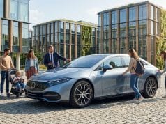 L’évolution du marché de la voiture électrique en 2026 Famille et professionnels autour d'une voiture électrique moderne devant un immeuble éco-conçu.