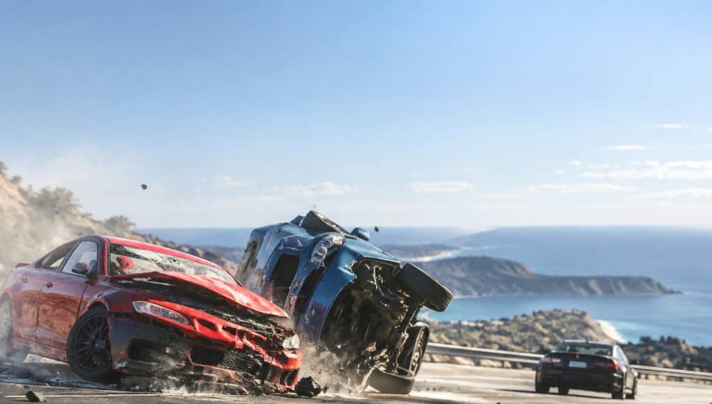 Une voiture rouge accidentée percute un SUV bleu renversé sur une route côtière dans le jeu BeamNG.drive.