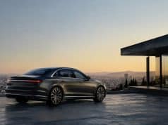 L’Audi A8 ne disparaîtra pas malgré des ventes faibles Une Audi A8 gris foncé stationnée sur une terrasse moderne surplombant une ville au coucher du soleil.