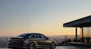 L’Audi A8 ne disparaîtra pas malgré des ventes faibles Une Audi A8 gris foncé stationnée sur une terrasse moderne surplombant une ville au coucher du soleil.