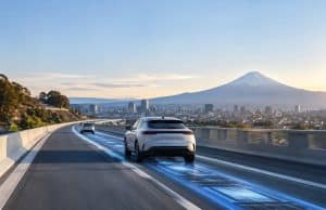 Honda et Taisei prévoient un test de recharge par induction au Japon Voitures électriques roulant sur une autoroute japonaise avec une animation lumineuse bleue illustrant la recharge sans fil.