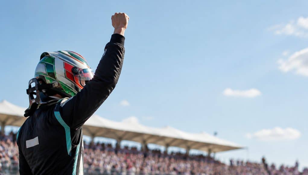 Kimi Antonelli vainqueur au GP des États-Unis 2026 Le pilote de F1 Kimi Antonelli célèbre sa victoire le poing levé, portant son casque de course face à une foule en liesse.