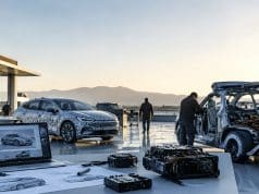 Accélération des cycles de conception automobile et complexification électronique : quels risques ? Ingénieurs travaillant sur des voitures prototypes et des composants électroniques en extérieur au coucher du soleil.