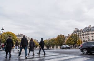 Conformité des passages piétons à Paris : loi LOM et sécurité routière Piétons traversant une rue à Paris sur un passage clouté sous un ciel gris.
